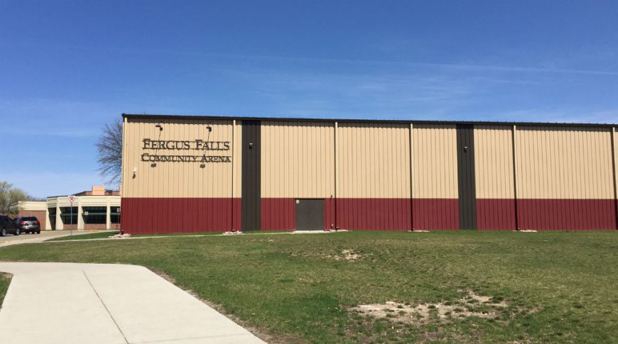 Exterior light brown, red, and dark brown metal building with words "Fergus Falls Community Arena" in metal sign.