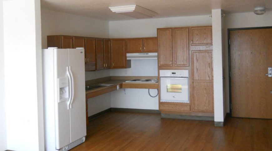 Honey oak interior kitchenette with white fridge and oven appliances.
