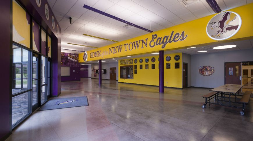 Bright purple and yellow painted walls on the entryway to school with the words "Home of the New Town Eagles" on upper wall with eagle emblem.