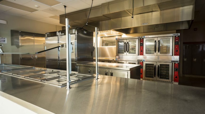 Industrial kitchen with stainless steel kitchen appliances and countertops throughout.