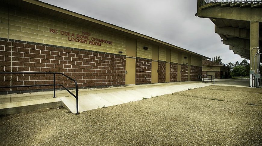 Brown brick locker room building besides concrete stadium seating