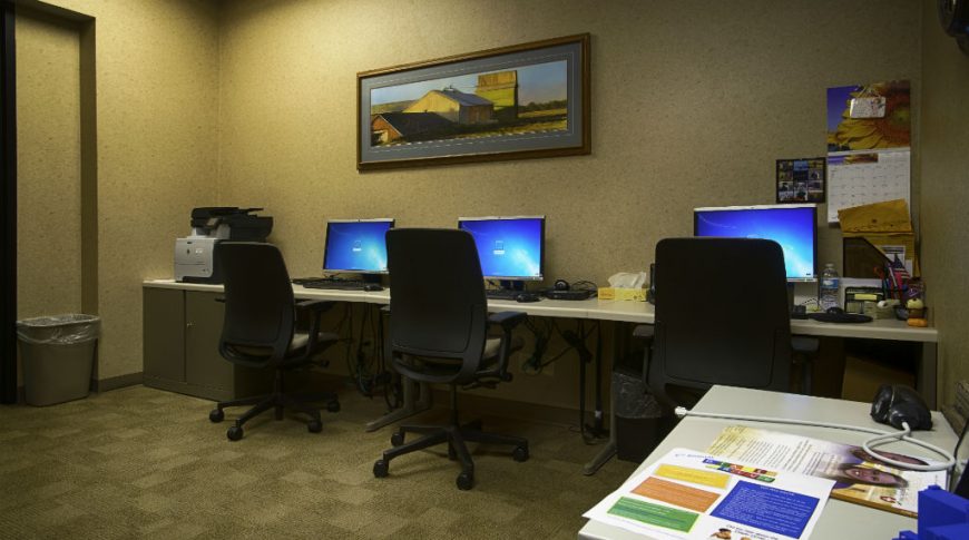 Beige speckled walls with 3 worktop stations with computer and chairs underneath