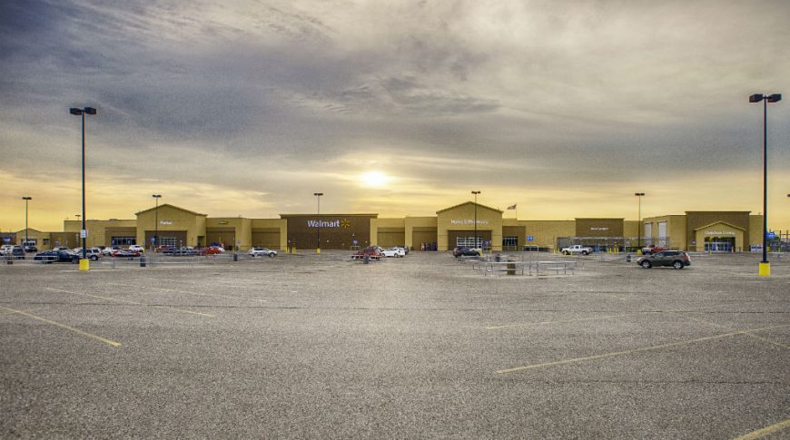 Back parking lot panorama view of brown brick walmart with brown accents and cloudy sky