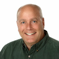 White middle-aged bald man with dark green button-up shirt on white background.