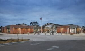 Fergus Falls Public Library with brick facade and American flag from street view at dusk.