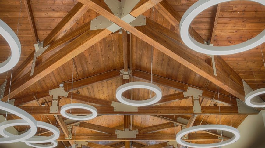 Pine stained ceiling with exposed wooden trusses and large ring lights