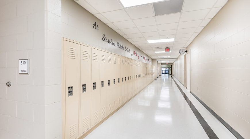Light beige hallway filled with light beige lockers and inspirational quotes above.