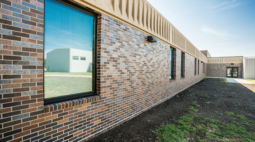 Exterior view of Sisseton Middle School showcasing shades of light and dark brown and gray bricks with sleek single pane windows across.