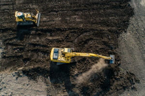 Bird's eye view of an excavator and bulldozer digging in a dirt field