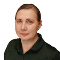 Portrait of middle-aged white woman with light-brown hair pulled back and bright green eyes wearing a dark green polo with the Comstock Construction logo.