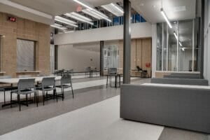 Back corner of high school commons area with long rectangular table and chairs and booths to the outside wall.