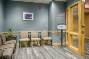 Hospital waiting room with steel blue/gray walls, maple wood finishes and chairs on back walls.